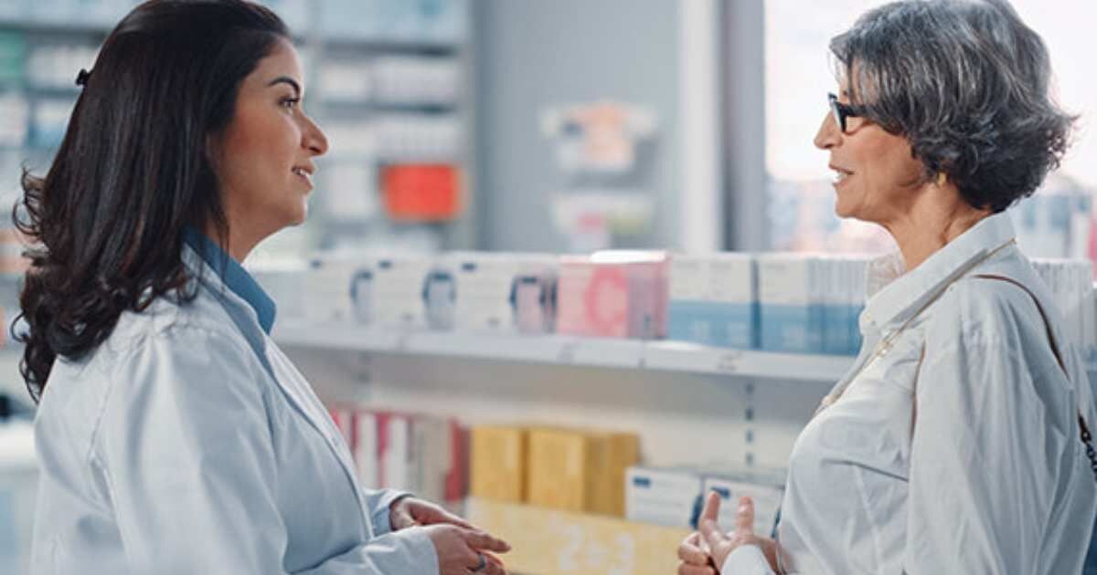 Pharmacist speaking with a customer in a pharmacy.