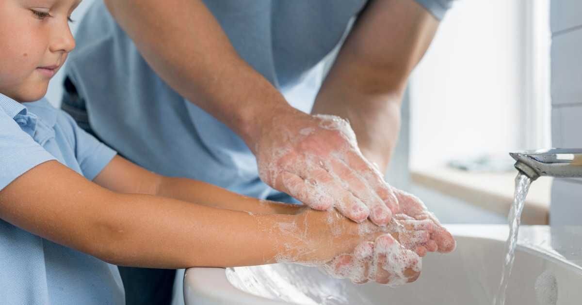 dad and son washing hands with soap in the sink