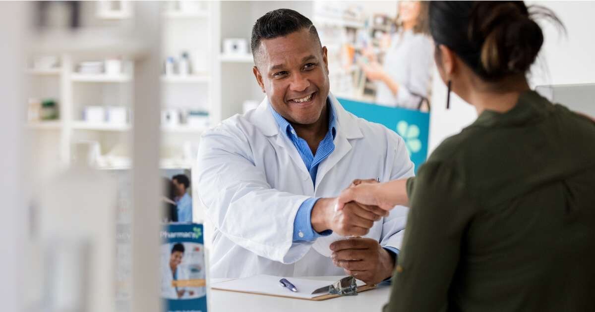 pharmacist and customer shaking hands while smiling 